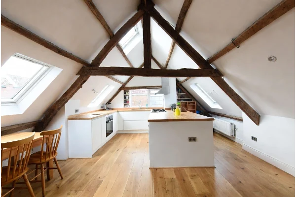 Completed loft conversion interior in a London home with exposed wooden beams and skylight windows