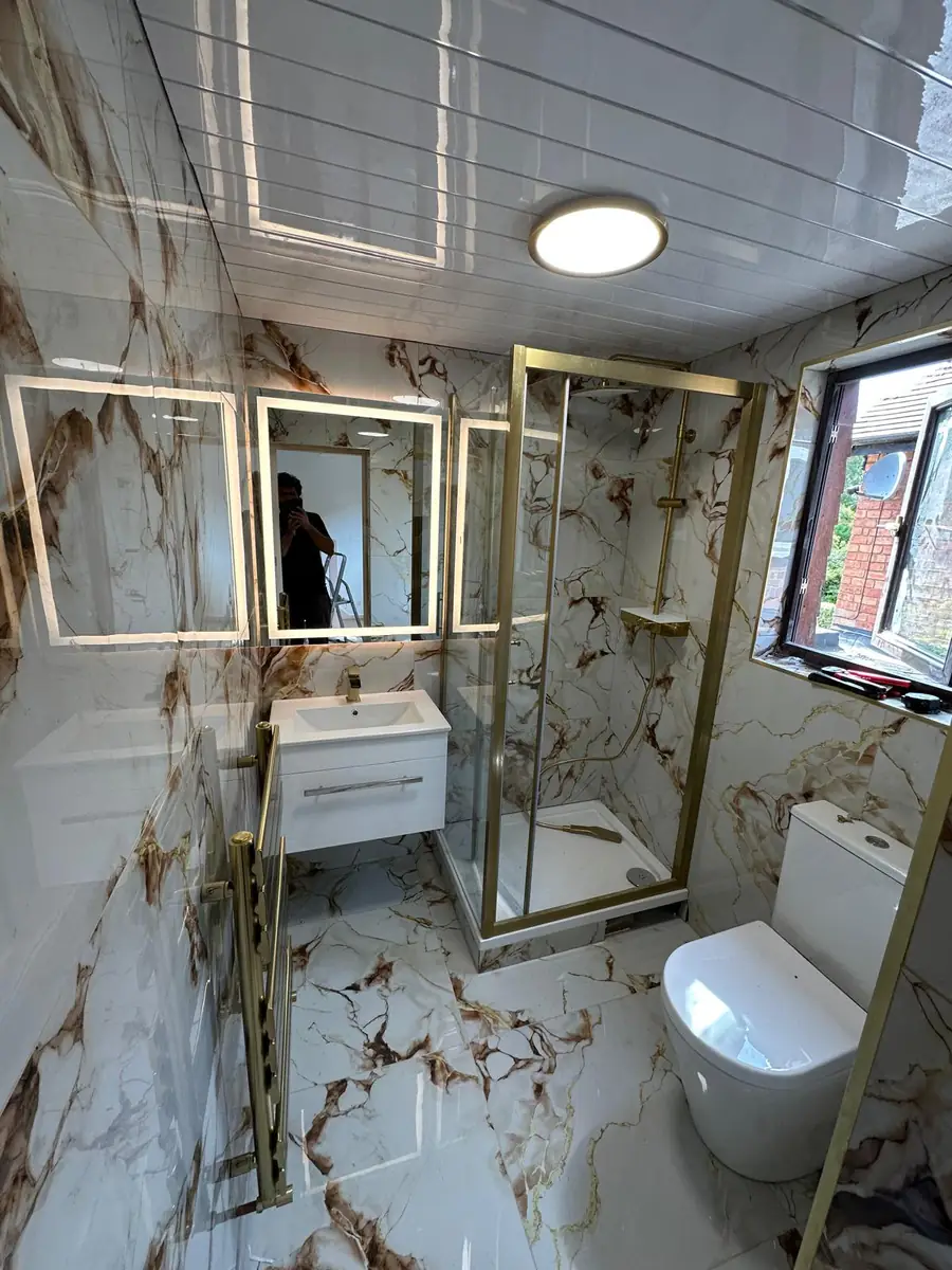 Bathroom renovation by Soraiz Builders in Brent showing the brushed-gold corner shower, back-to-wall toilet, heated towel rail and LED mirror cabinet