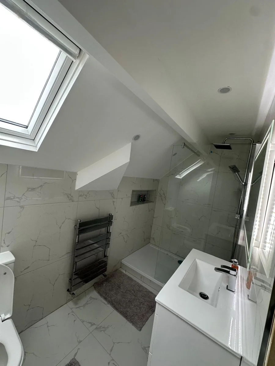 Finished marble-effect tiled ensuite in a Croydon loft, with a walk-in shower, WC, vanity and sloped ceiling downlights