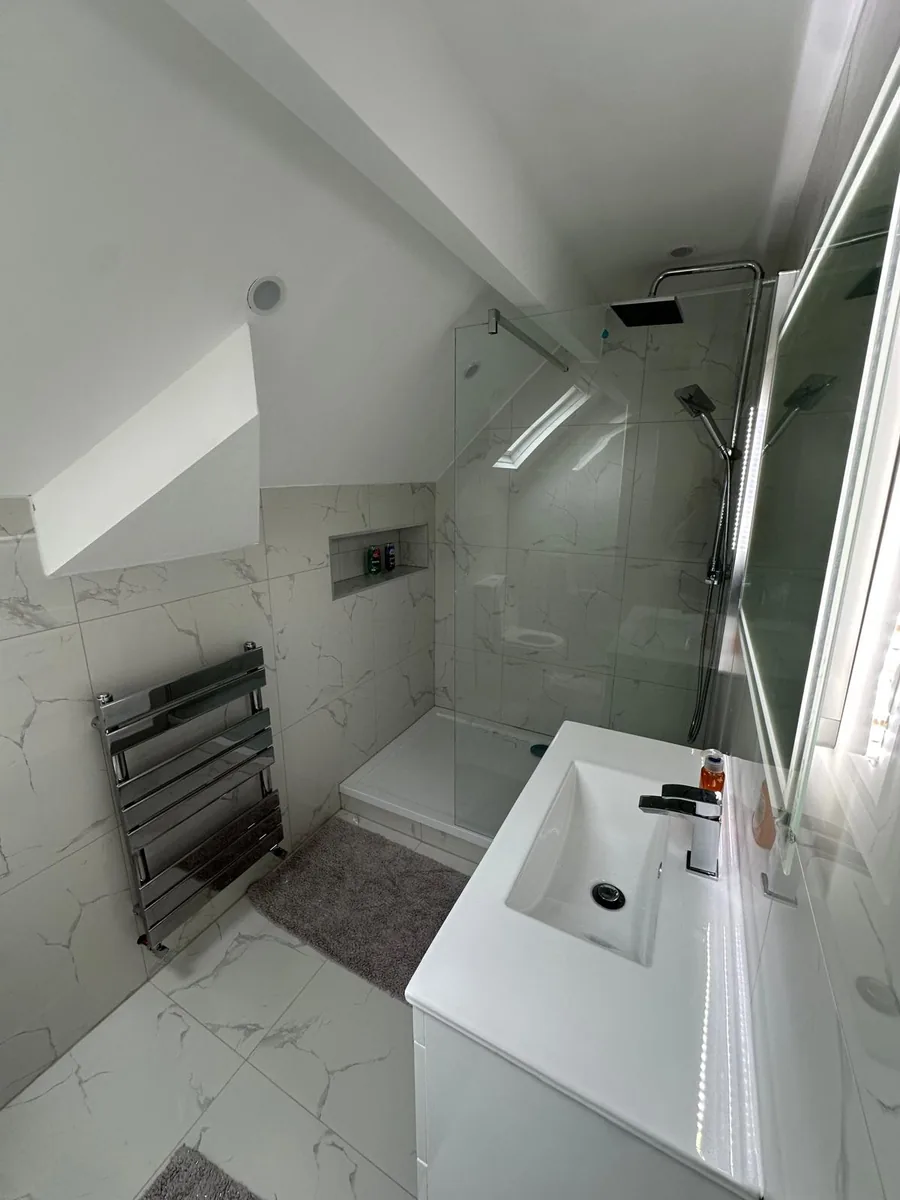 Finished Croydon loft bathroom with a glass walk-in shower, wall-hung vanity unit, LED mirror and chrome heated towel rail