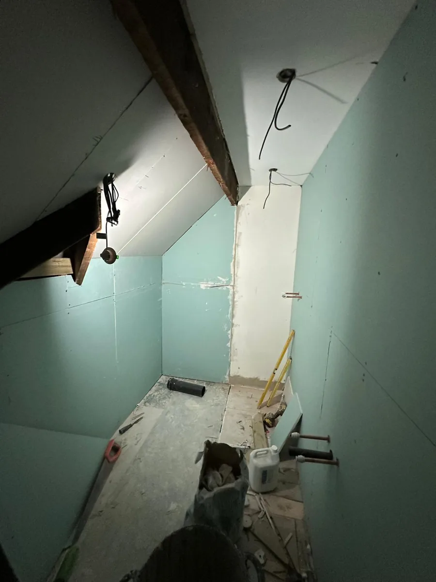 Croydon loft bathroom under construction, walls lined with moisture-resistant plasterboard and first-fix plumbing run into the floor