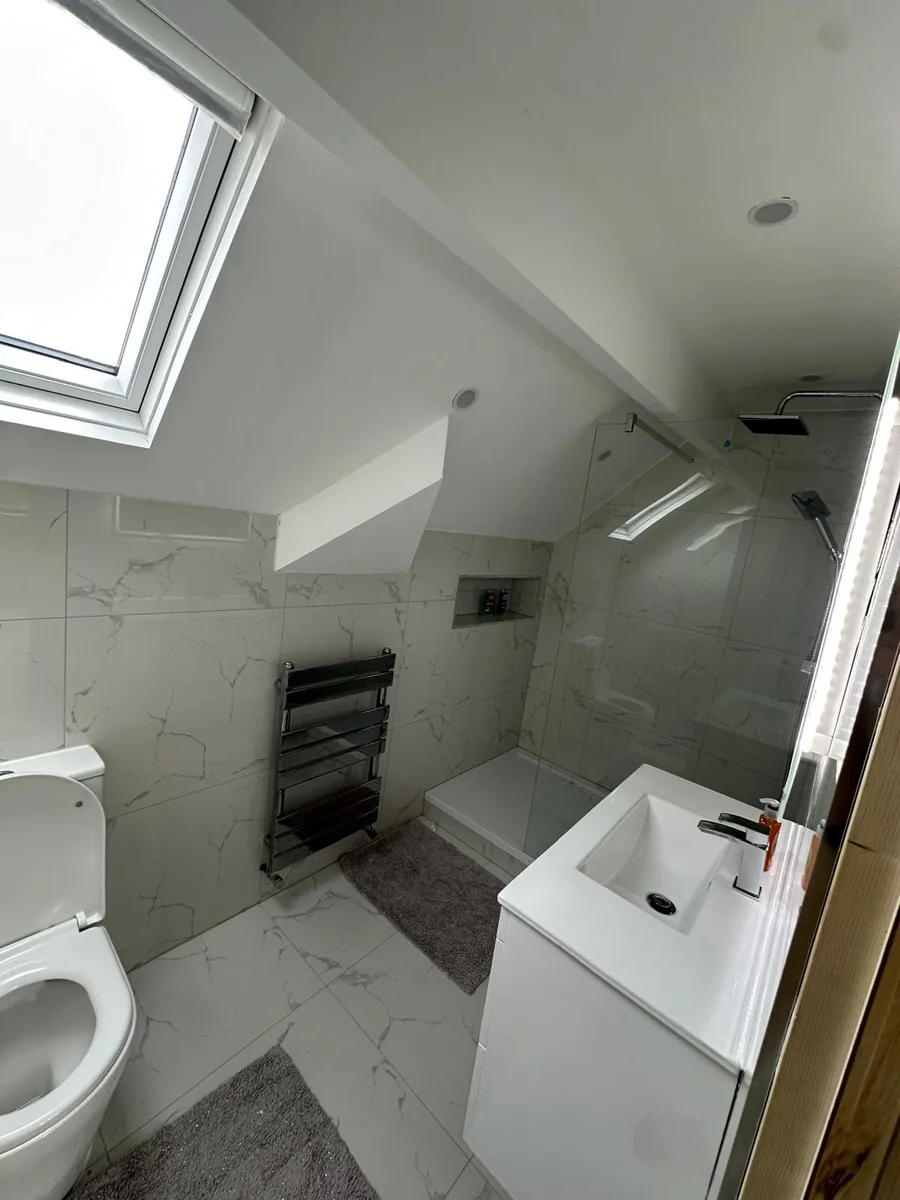 Completed loft conversion in Croydon, a new ensuite shower room with marble-effect tiling, a walk-in shower and a Velux roof window