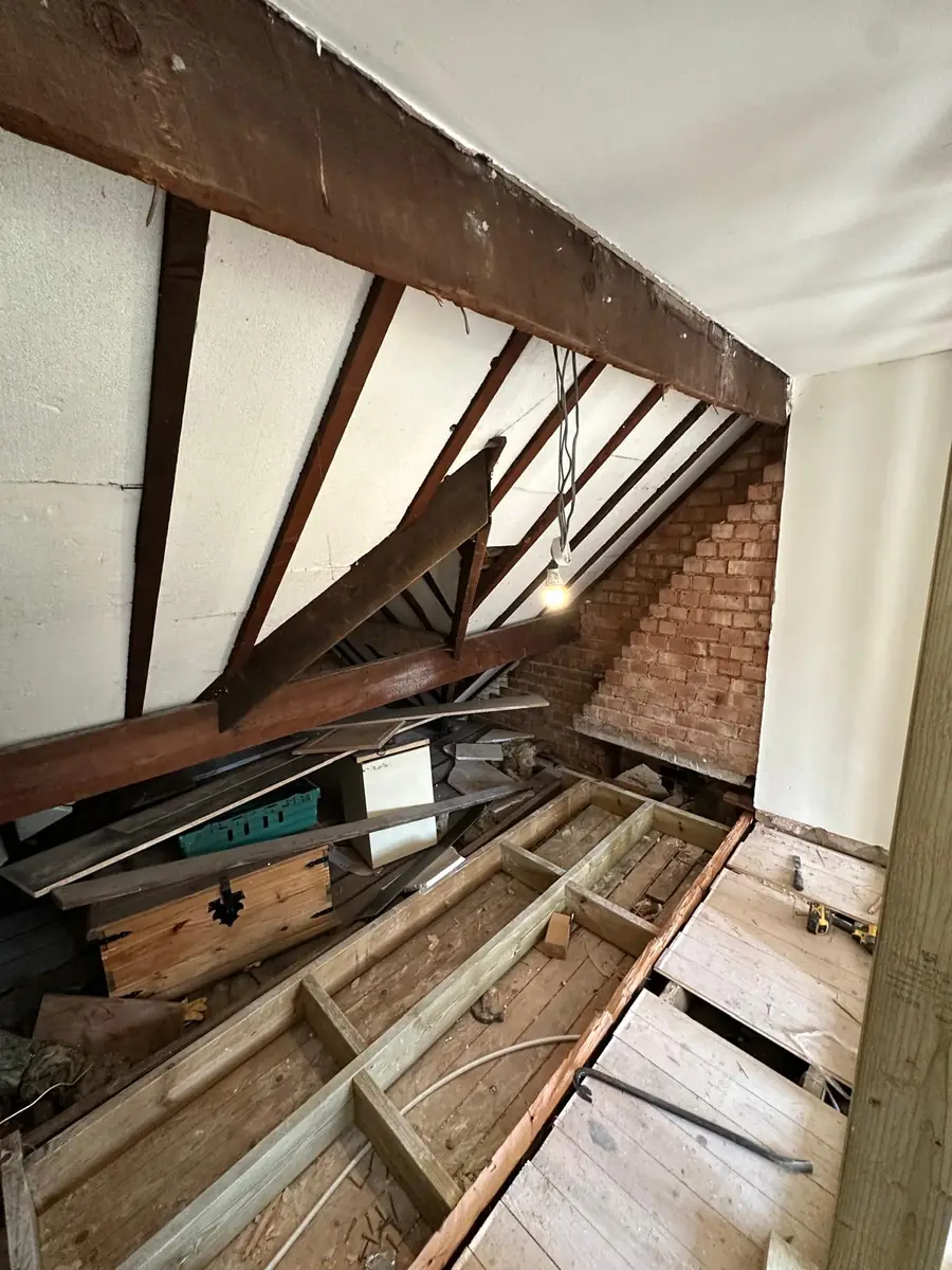 Original unconverted loft in Croydon before work, with exposed roof timbers, an old brick chimney stack and bare floor joists