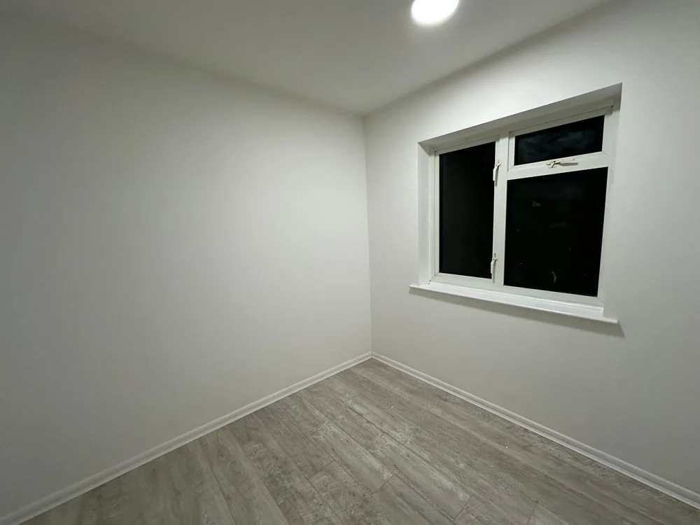 Finished bedroom with smooth white walls, white skirting and grey oak-effect flooring after renovation, Sidcup