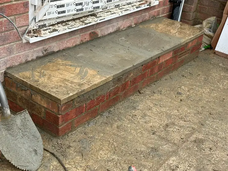 A new red brick planter wall with stone coping built against a house front in North Greenford