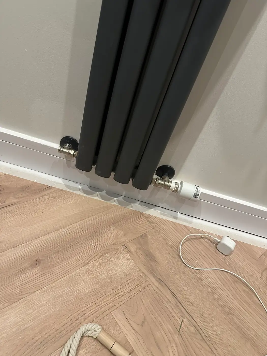 The lower half of a new anthracite vertical column radiator with its valves, fitted in a Rotherhithe flat