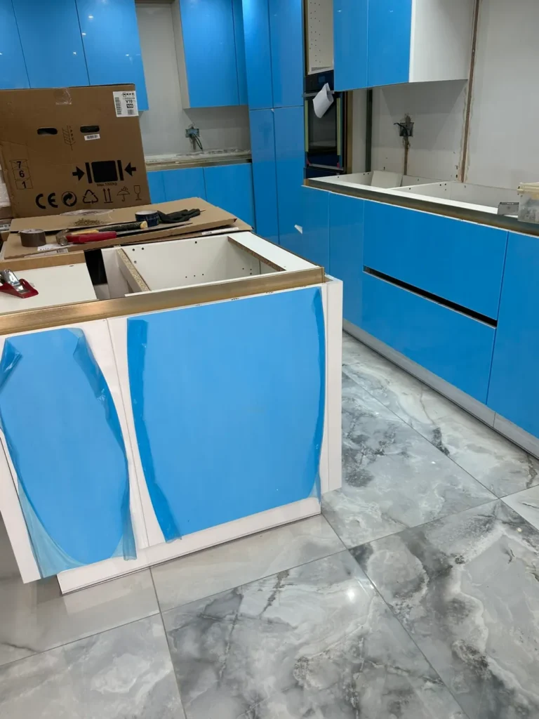 A blue gloss kitchen and island being installed on a marble-effect tiled floor, Stanborough, Watford