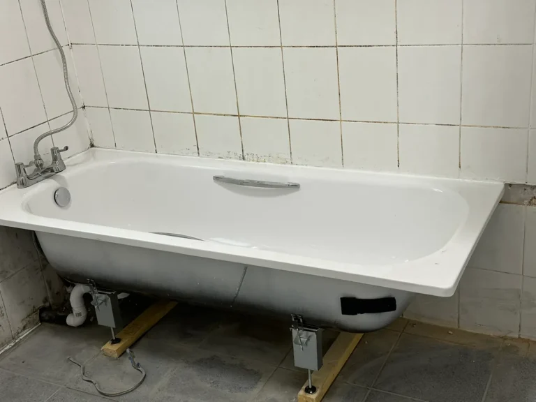 A new bath being fitted in the bathroom, Wembley Central