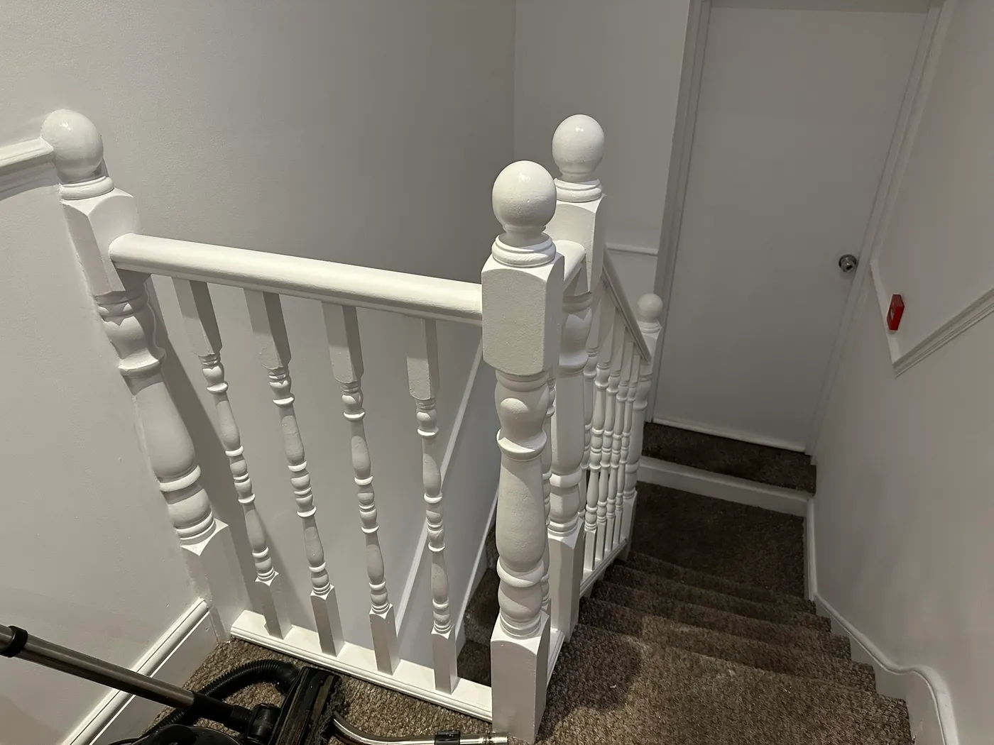 Turned spindles, newel posts and handrail freshly painted in white gloss on a staircase in Woolwich